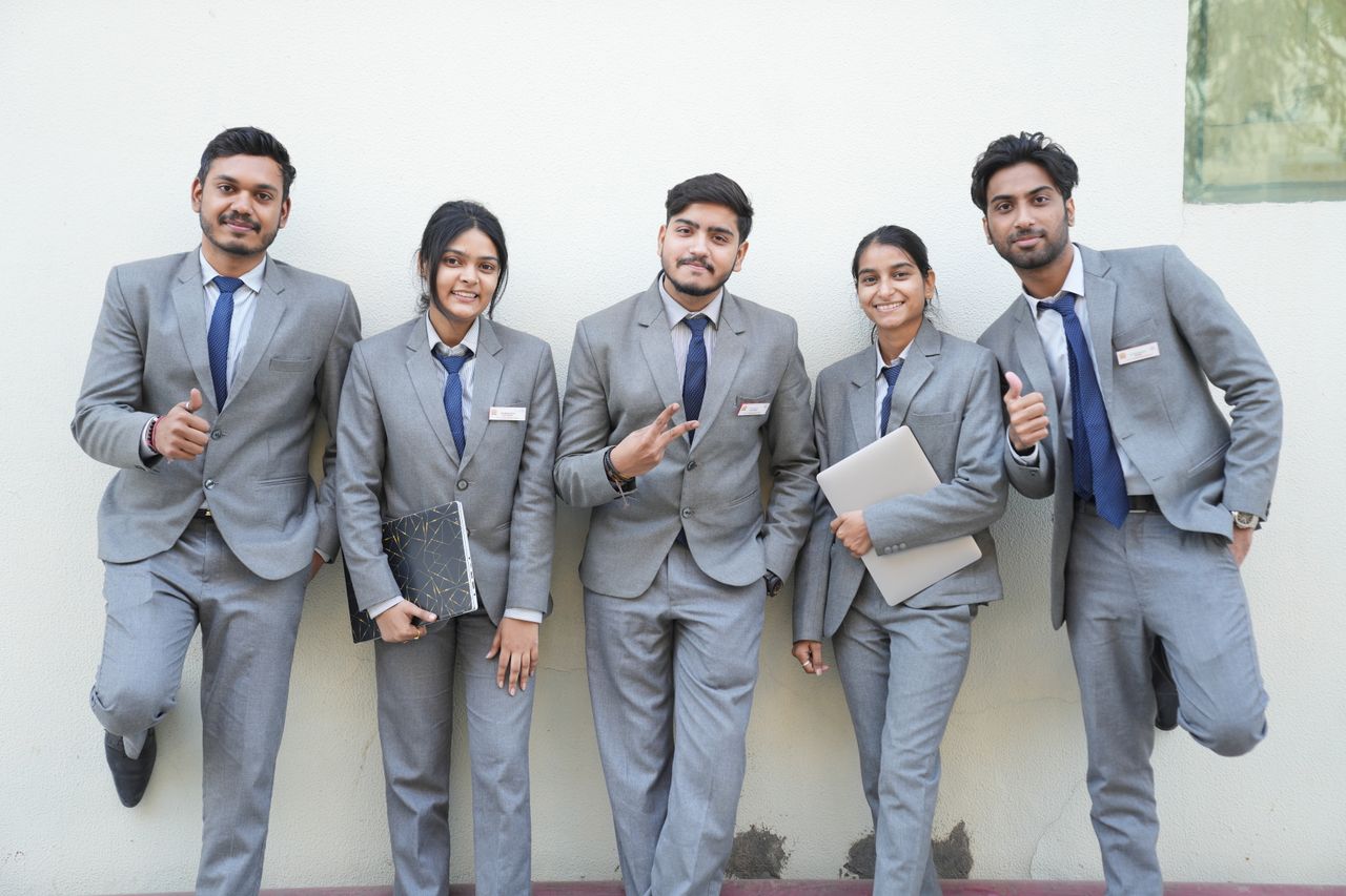 Services Group of young professionals in formal suits posing with smiles and confidence against a wall.